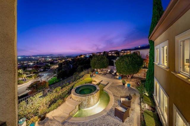 patio terrace at dusk featuring a fenced backyard and an in ground hot tub