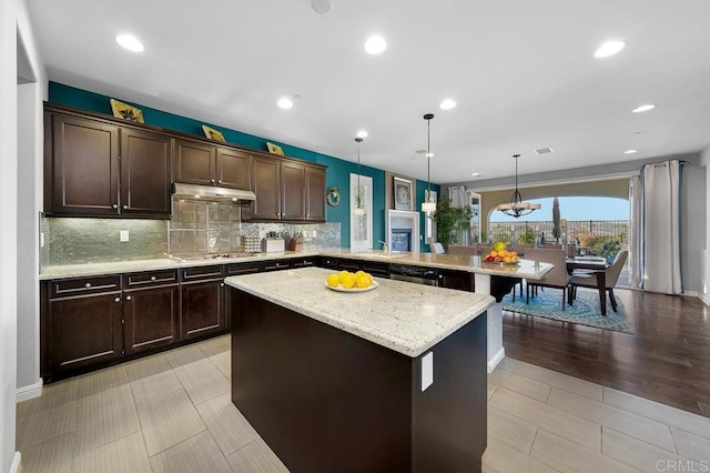 kitchen with stainless steel appliances, hanging light fixtures, a kitchen island, a peninsula, and under cabinet range hood