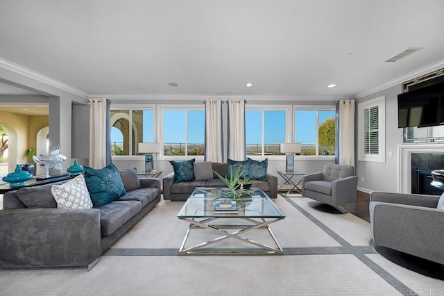 living area with crown molding, recessed lighting, visible vents, a glass covered fireplace, and baseboards