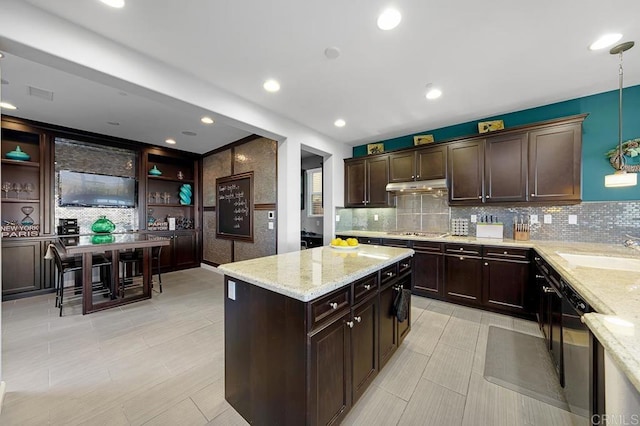 kitchen featuring pendant lighting, under cabinet range hood, a sink, a center island, and stainless steel gas stovetop