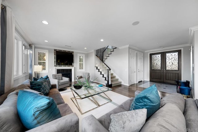 living room with recessed lighting, wood finished floors, stairs, ornamental molding, and a tiled fireplace