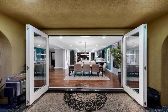 sunroom with an inviting chandelier, arched walkways, and french doors