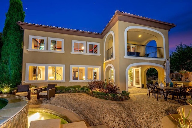 back of house featuring a patio area, a balcony, and stucco siding