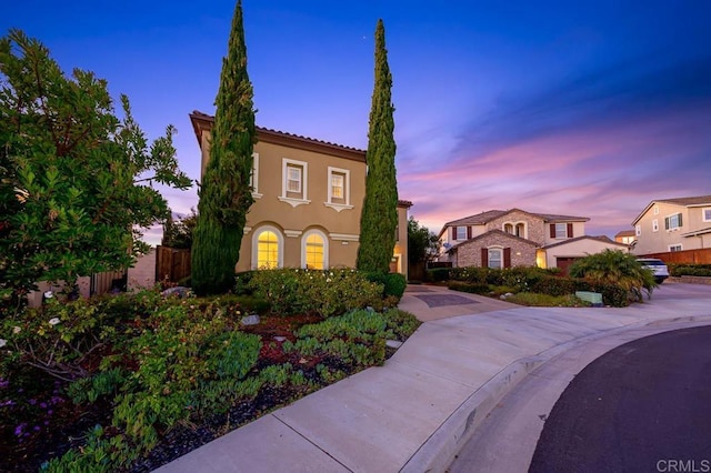 mediterranean / spanish-style home with fence and stucco siding