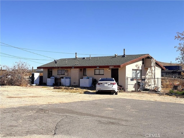 single story home with roof with shingles, fence, and stucco siding