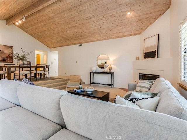 living area with visible vents, lofted ceiling with beams, a glass covered fireplace, carpet flooring, and wooden ceiling