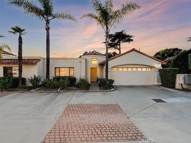 mediterranean / spanish home featuring driveway, an attached garage, and stucco siding