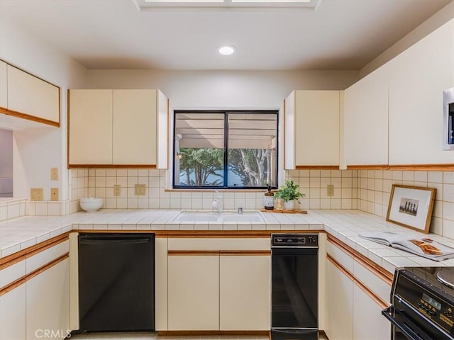 kitchen with tile countertops, black dishwasher, backsplash, and a sink