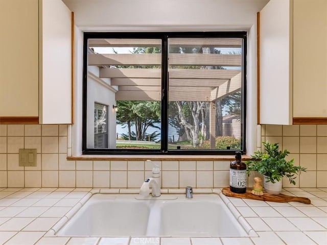 details with backsplash, a sink, tile counters, and white cabinets