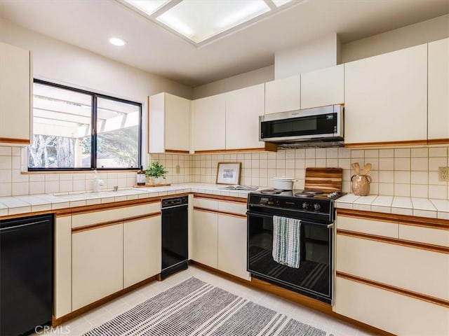 kitchen featuring white cabinetry, black range with electric cooktop, stainless steel microwave, and a sink