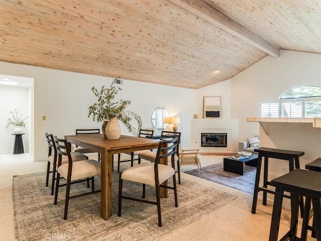 carpeted dining area featuring a glass covered fireplace, wooden ceiling, and vaulted ceiling with beams