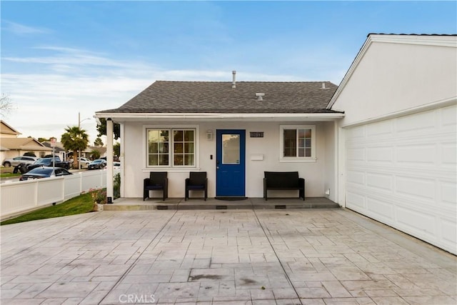 back of house featuring roof with shingles, fence, and stucco siding