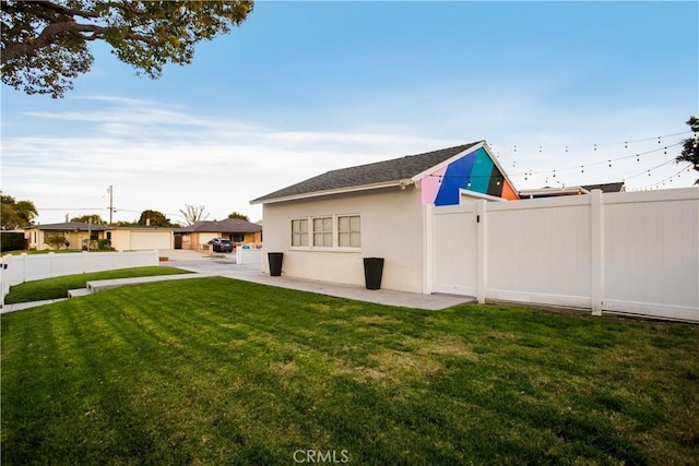 rear view of property featuring stucco siding, a lawn, and fence