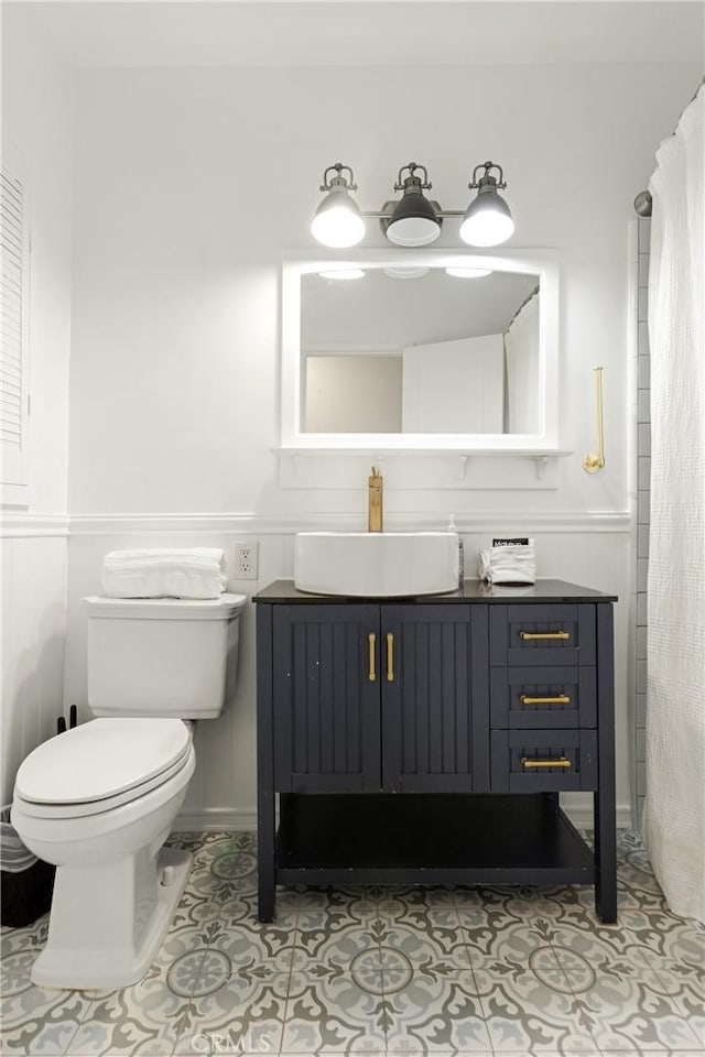 full bathroom with toilet, a wainscoted wall, tile patterned flooring, and vanity