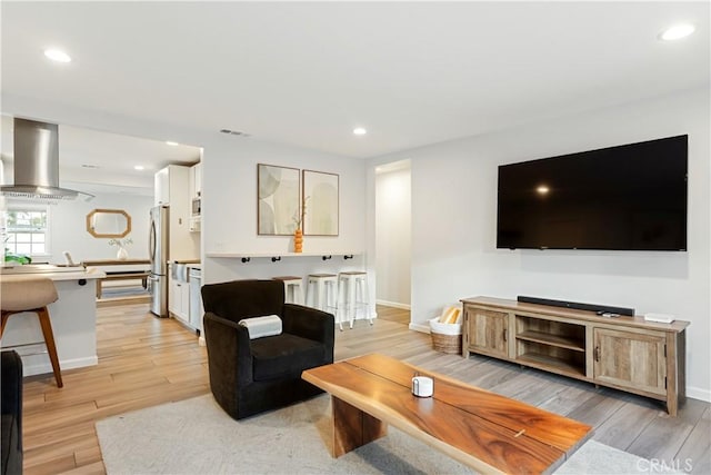 living area with recessed lighting, visible vents, light wood-style flooring, and baseboards