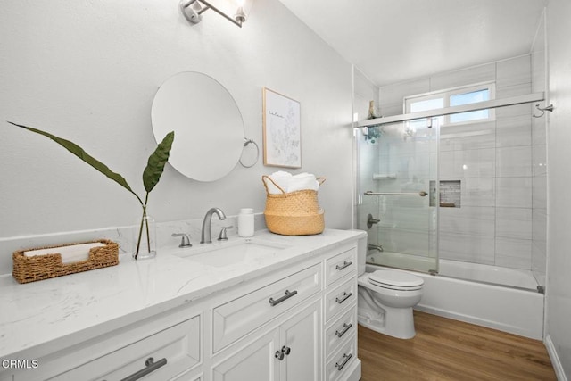 bathroom with combined bath / shower with glass door, vanity, toilet, and wood finished floors