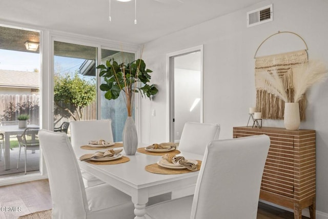 dining area with a wall of windows, wood finished floors, and visible vents