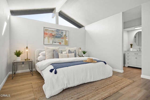 bedroom featuring vaulted ceiling with beams, light wood-style floors, and baseboards