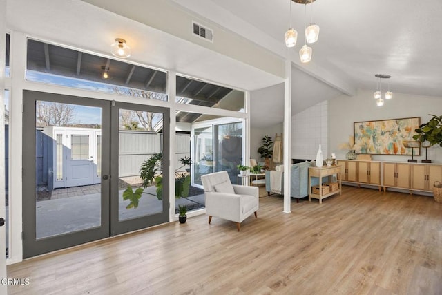 living area featuring french doors, vaulted ceiling with beams, visible vents, wood finished floors, and a chandelier