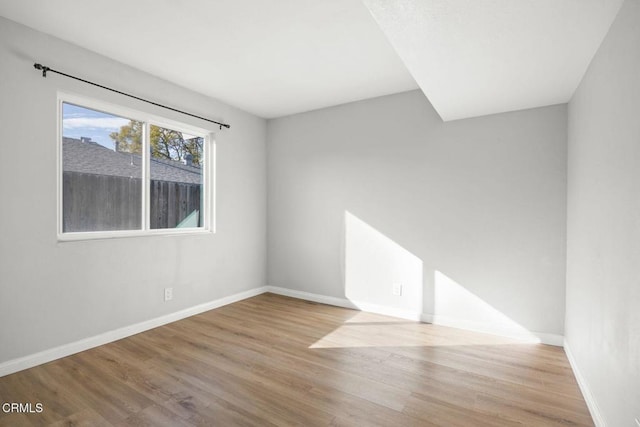 spare room featuring baseboards and wood finished floors