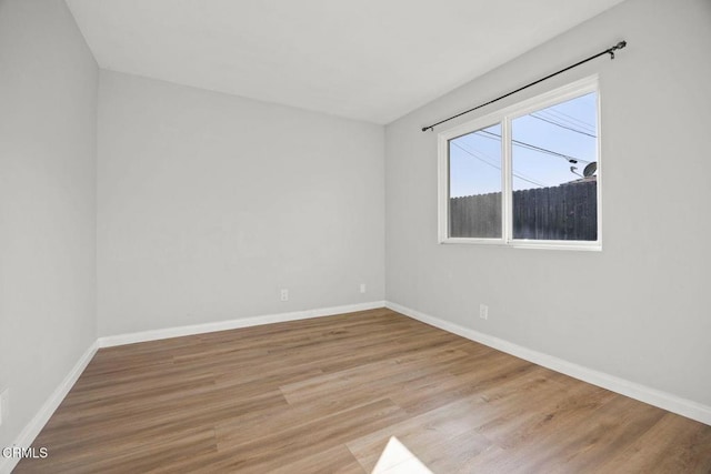 spare room featuring baseboards and wood finished floors