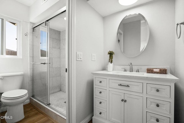 full bath featuring a stall shower, baseboards, toilet, wood finished floors, and vanity