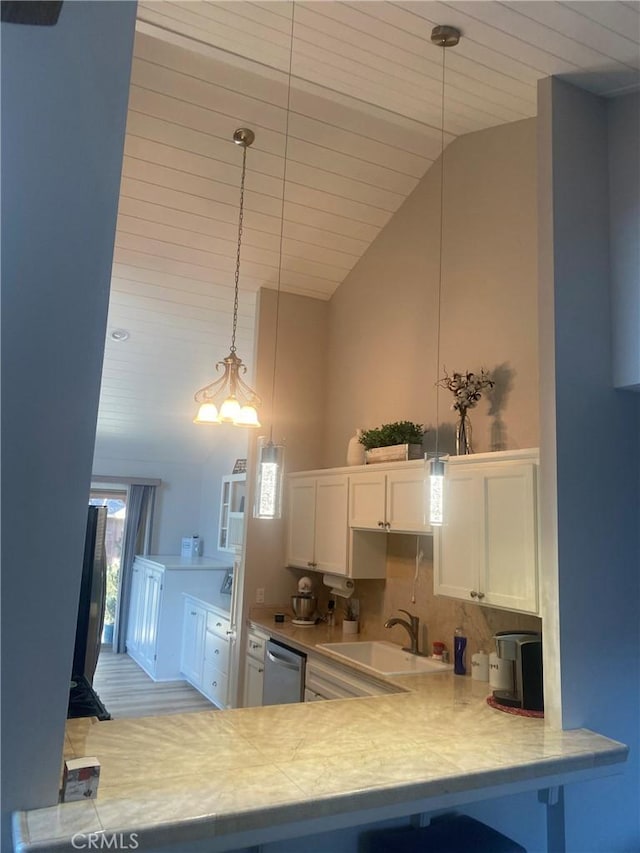 kitchen featuring light countertops, hanging light fixtures, white cabinetry, a sink, and dishwasher