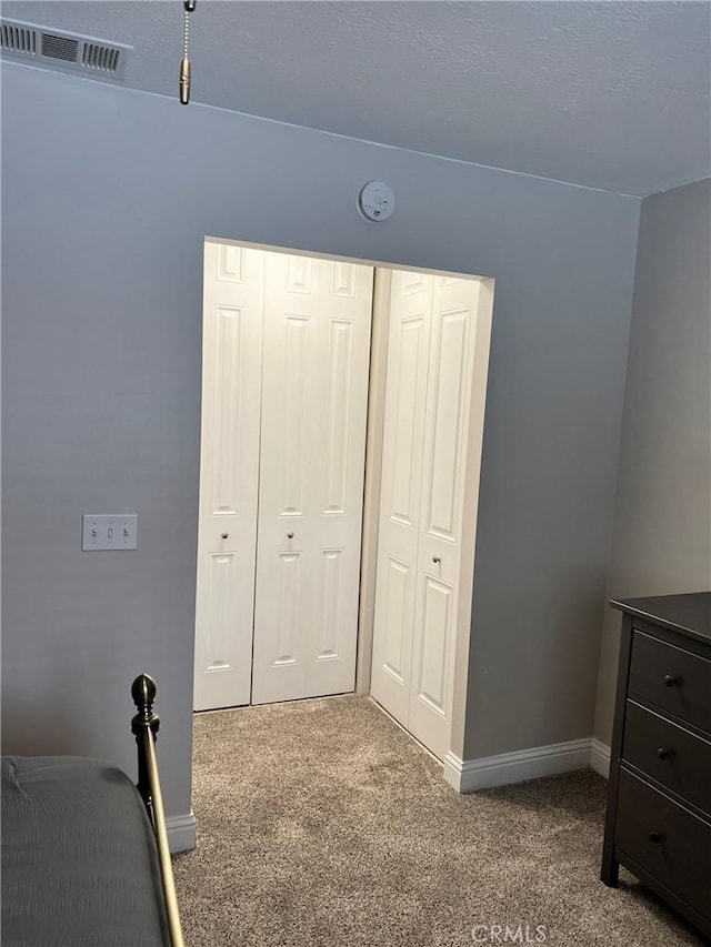 unfurnished bedroom with a closet, carpet, visible vents, and baseboards