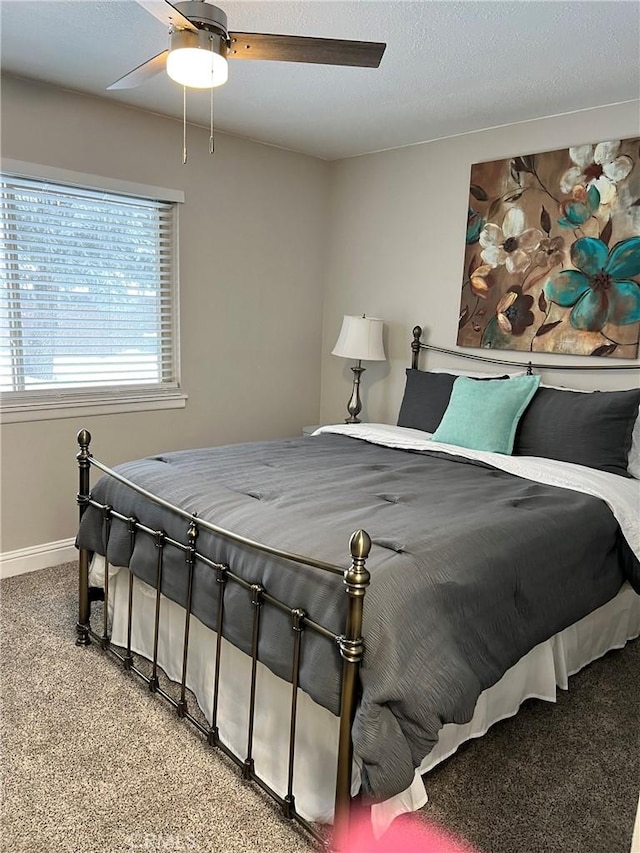 bedroom with carpet, a textured ceiling, baseboards, and a ceiling fan