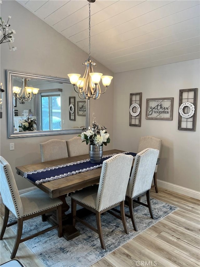 dining room featuring vaulted ceiling, wood finished floors, a chandelier, and baseboards