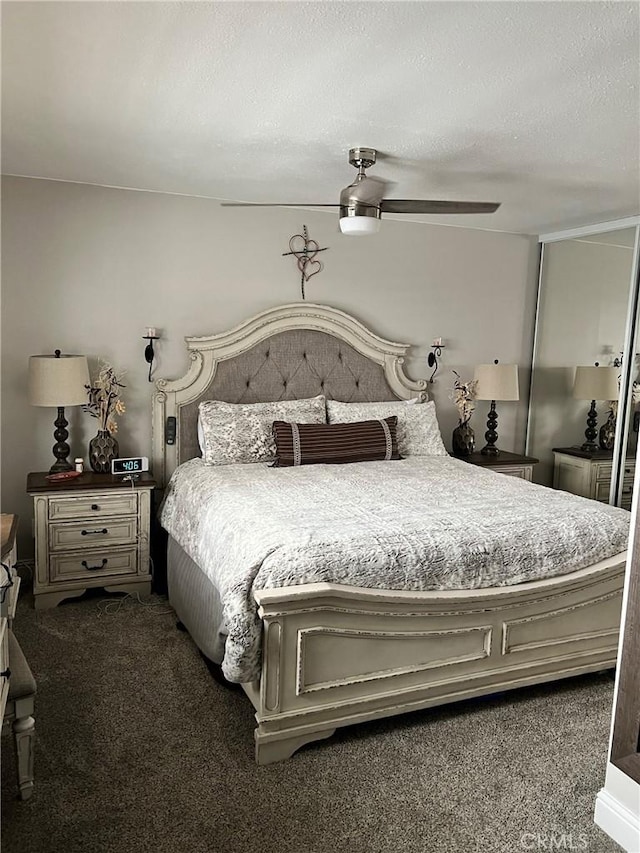 bedroom featuring ceiling fan, dark colored carpet, and a textured ceiling