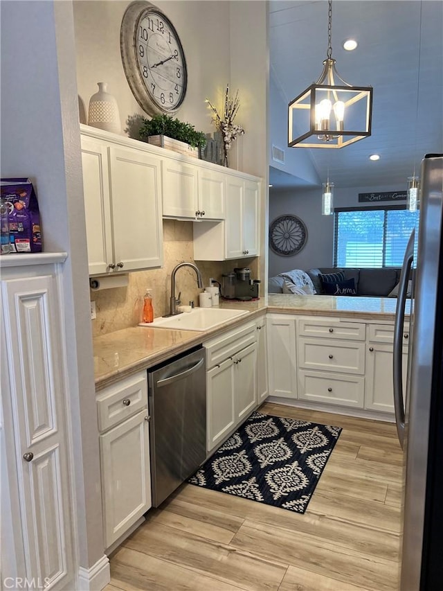 kitchen with appliances with stainless steel finishes, a sink, white cabinets, and pendant lighting