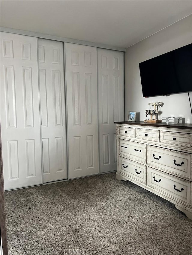 unfurnished bedroom with dark colored carpet and a closet