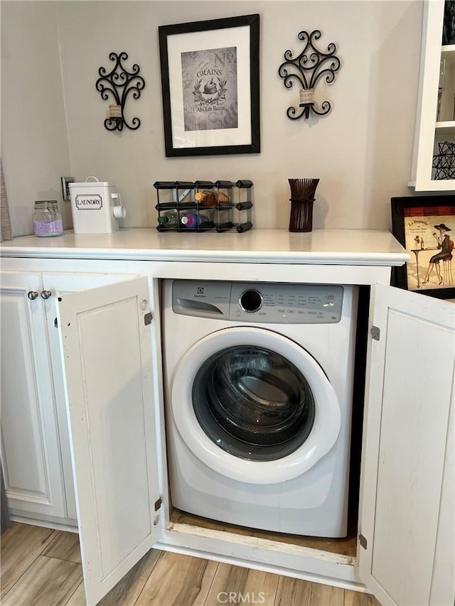 laundry area featuring washer / dryer, cabinet space, and light wood-style floors