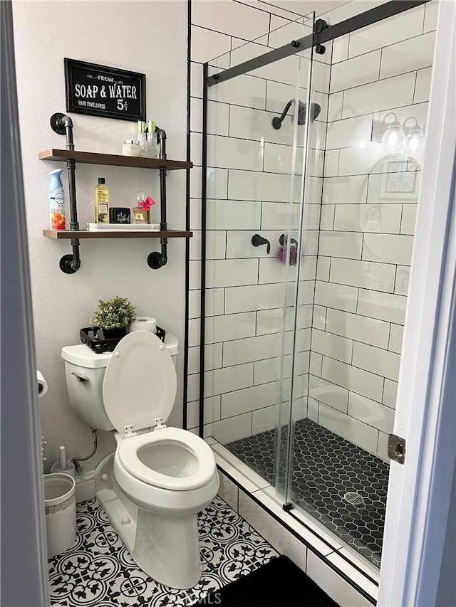 bathroom featuring toilet, a stall shower, baseboards, and tile patterned floors