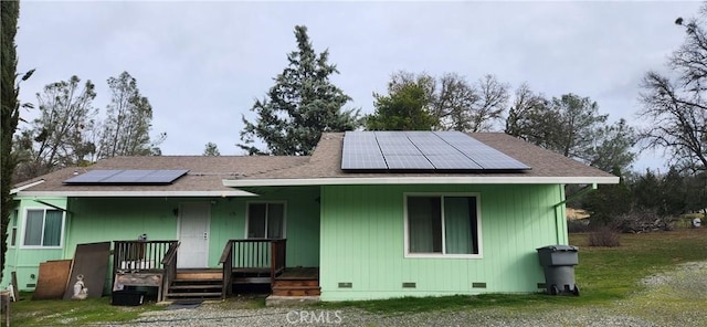 back of house featuring crawl space, covered porch, and solar panels