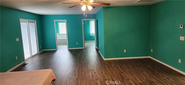 spare room with dark wood-style flooring, visible vents, ceiling fan, and baseboards