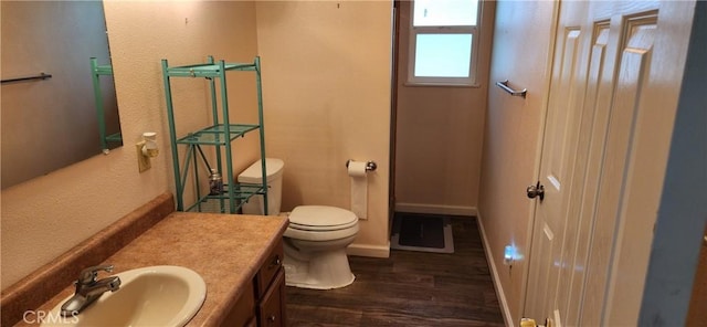 bathroom with toilet, baseboards, wood finished floors, and vanity