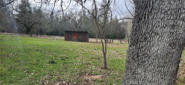 view of yard with a storage unit, a rural view, an outdoor structure, and fence