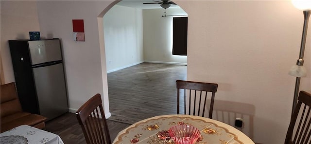 dining area featuring a ceiling fan, arched walkways, baseboards, and wood finished floors