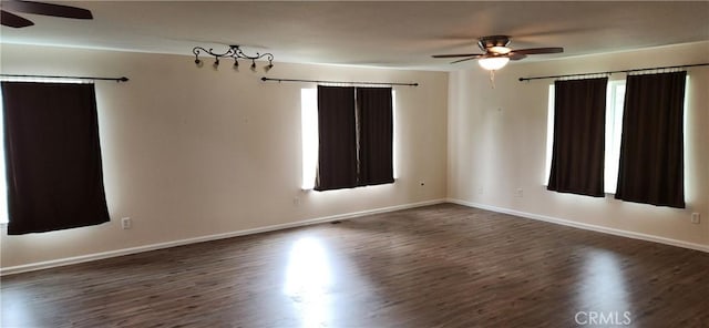 spare room featuring plenty of natural light, ceiling fan, baseboards, and dark wood finished floors