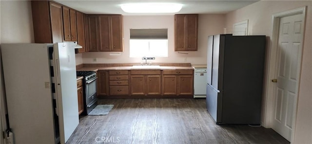 kitchen featuring dark wood-style flooring, a sink, light countertops, appliances with stainless steel finishes, and brown cabinetry