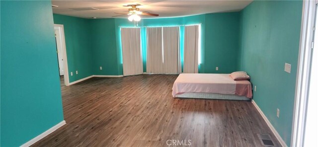 unfurnished bedroom with a ceiling fan, wood finished floors, visible vents, and baseboards