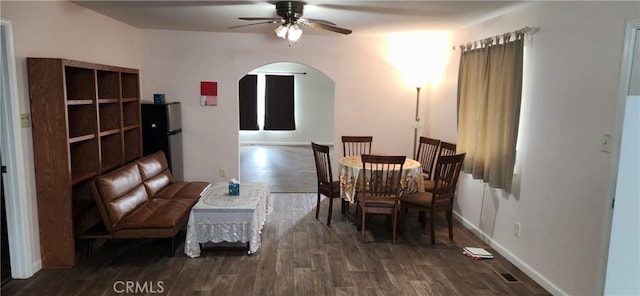 dining space featuring baseboards, ceiling fan, arched walkways, and wood finished floors