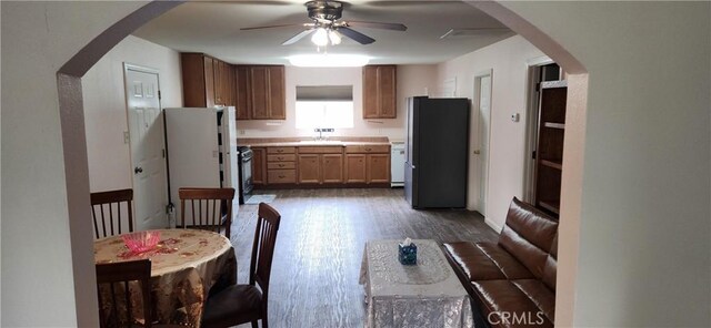 kitchen with dark wood-style floors, arched walkways, light countertops, and freestanding refrigerator