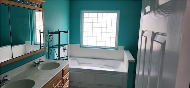 bathroom featuring a healthy amount of sunlight, a jetted tub, and a sink