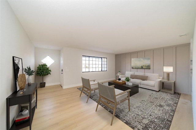 living area featuring light wood-type flooring, visible vents, and baseboards