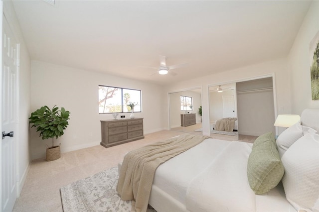 bedroom featuring two closets, a ceiling fan, light carpet, vaulted ceiling, and baseboards