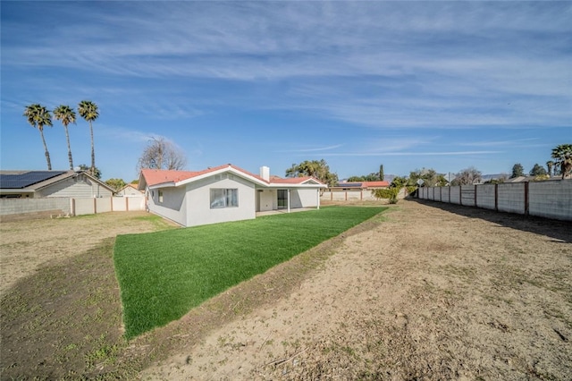 back of property with a fenced backyard, a yard, and stucco siding