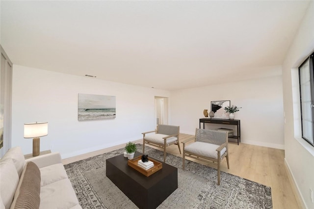 living room featuring light wood finished floors, visible vents, and baseboards